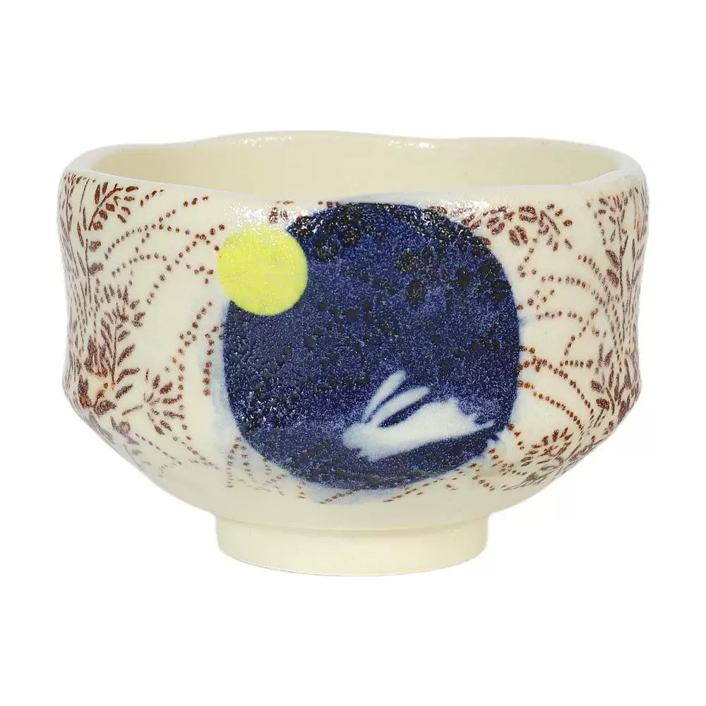 Close-up of a Japanese matcha bowl with a dark blue circle, white rabbit, and subtle brown botanical pattern.