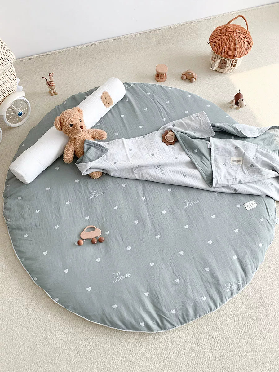 Round grey-blue baby play mat with small white hearts, featuring a sleeping baby.