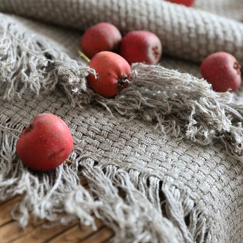 Textured grey linen throw blanket with fringes, styled with red berries.