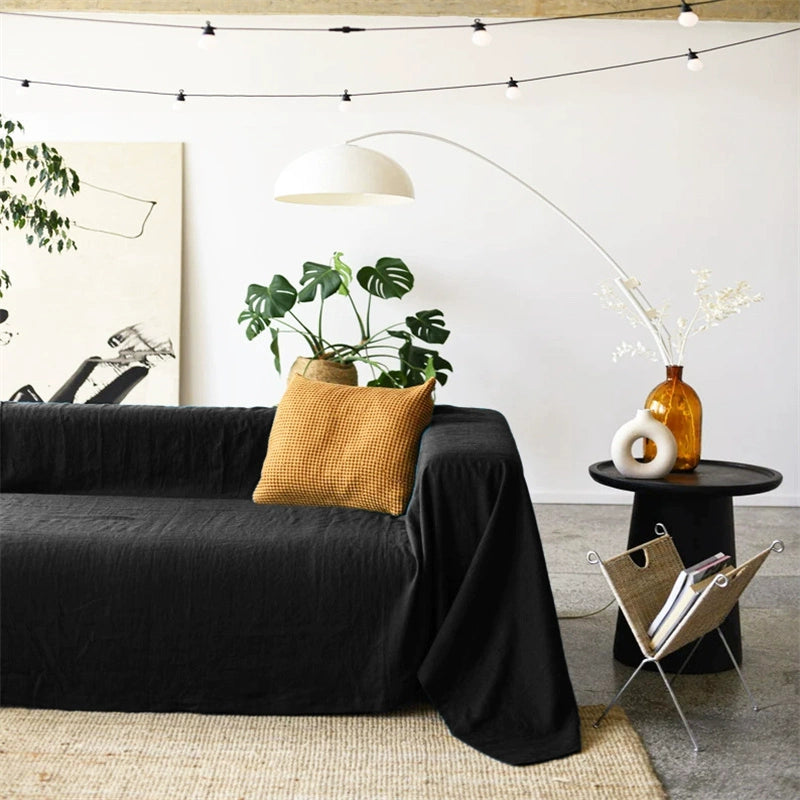 Mustard yellow linen sofa throw blanket draped over a dark sofa, cozy living room decor.