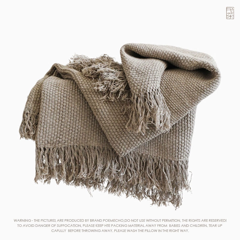 Natural linen throw blanket with fringes, textured weave in neutral tones.