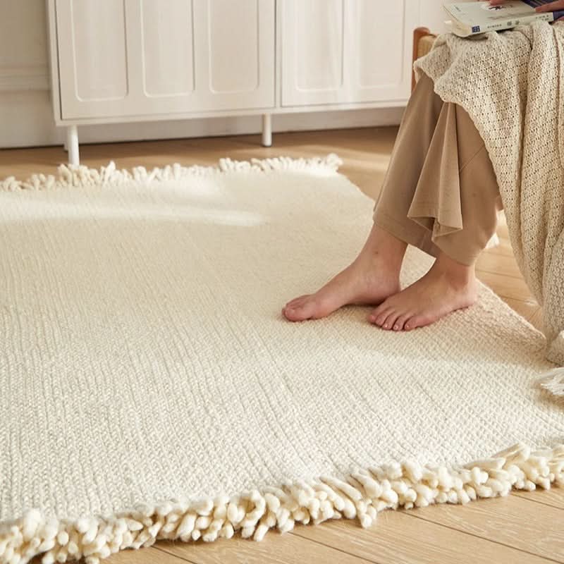 Cream braided wool rug with fringe detail, styled in a cozy living room setting.