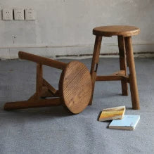 Two rustic wooden stools, natural finish, round tops, simple legs,  on light-colored floor.