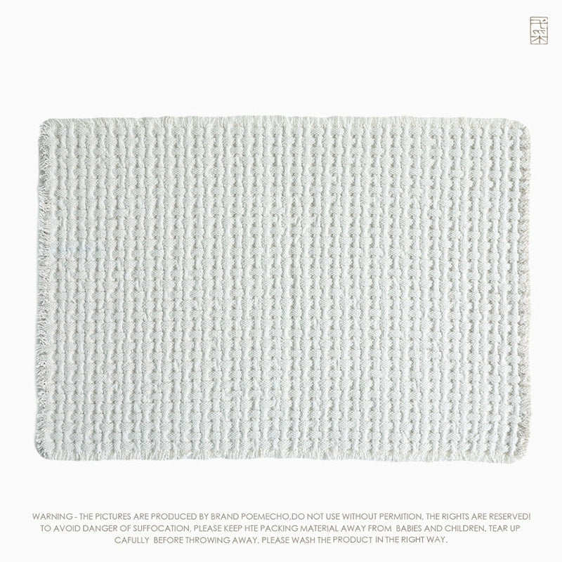Light beige woven cotton throw blanket with a textured, grid pattern.  Fringed edges.
