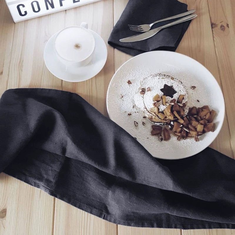 Dark grey linen table napkins accent a breakfast setting with pancakes and coffee.