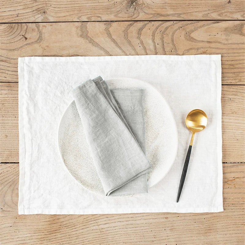 Elegant Linen Table Napkins in gray and white are elegantly set with a gold spoon on a wooden table.