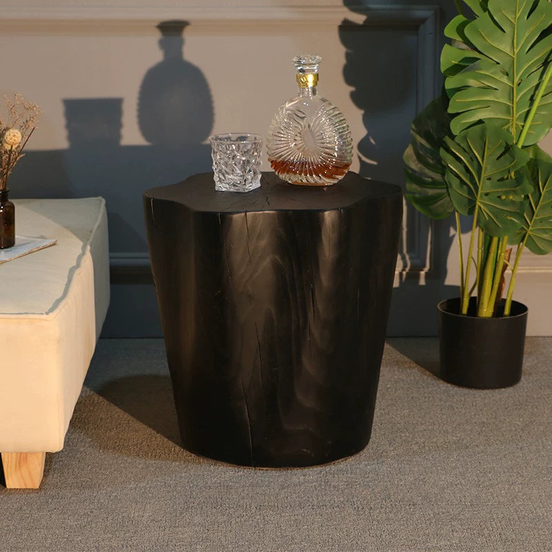 Dark brown wooden log side table, rustic style.  Natural wood grain and knots visible.  Small glass drinkware and bottle on top.  Roomy surface.