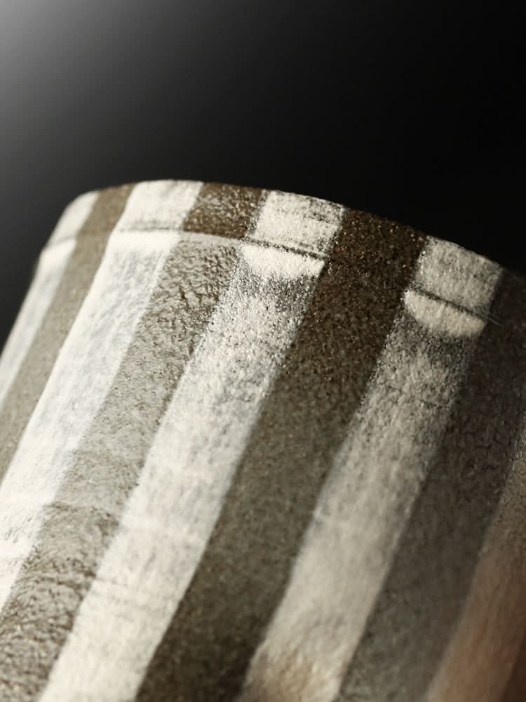 Textured ceramic handcrafted rustic coffee cup with vertical stripes in brown and white.