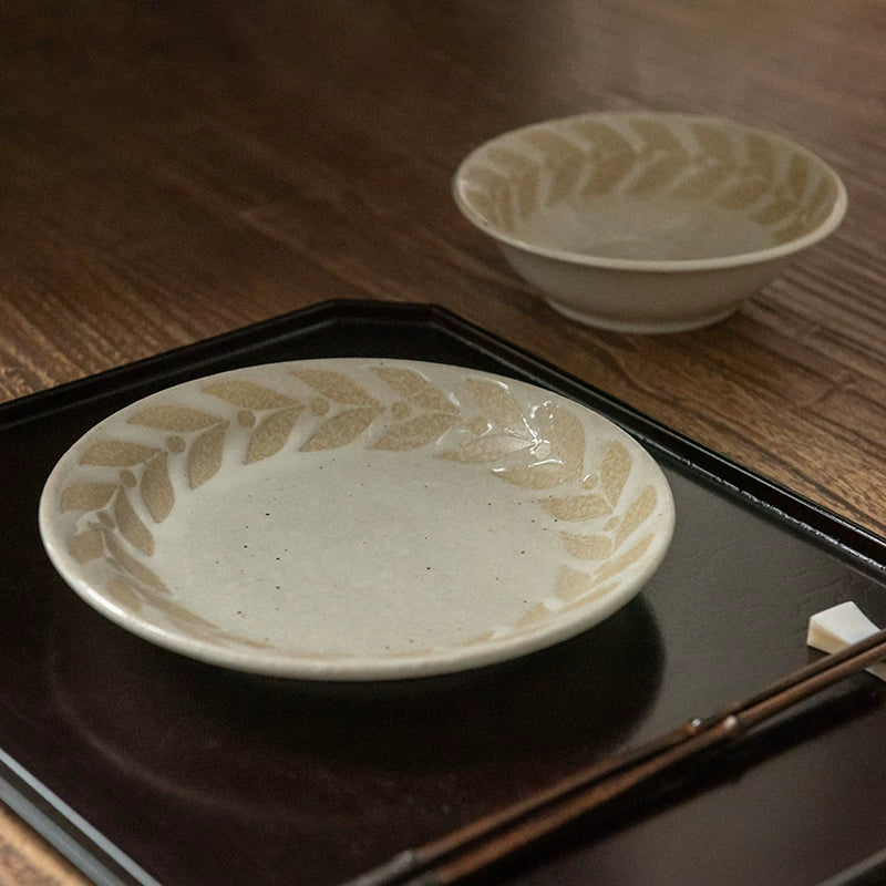 Shallow ceramic bowl with leaf pattern on a dark rectangular serving tray.