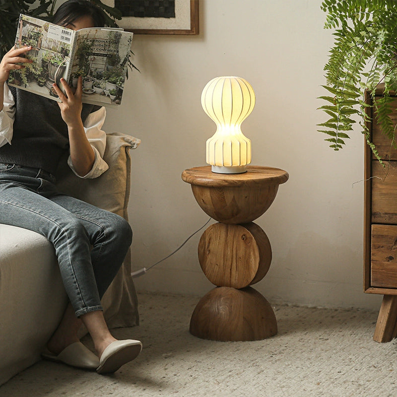 Light brown wooden round side table with stacked design.  Features three stacked circles, a round tabletop, and a lamp.  Natural wood grain visible.