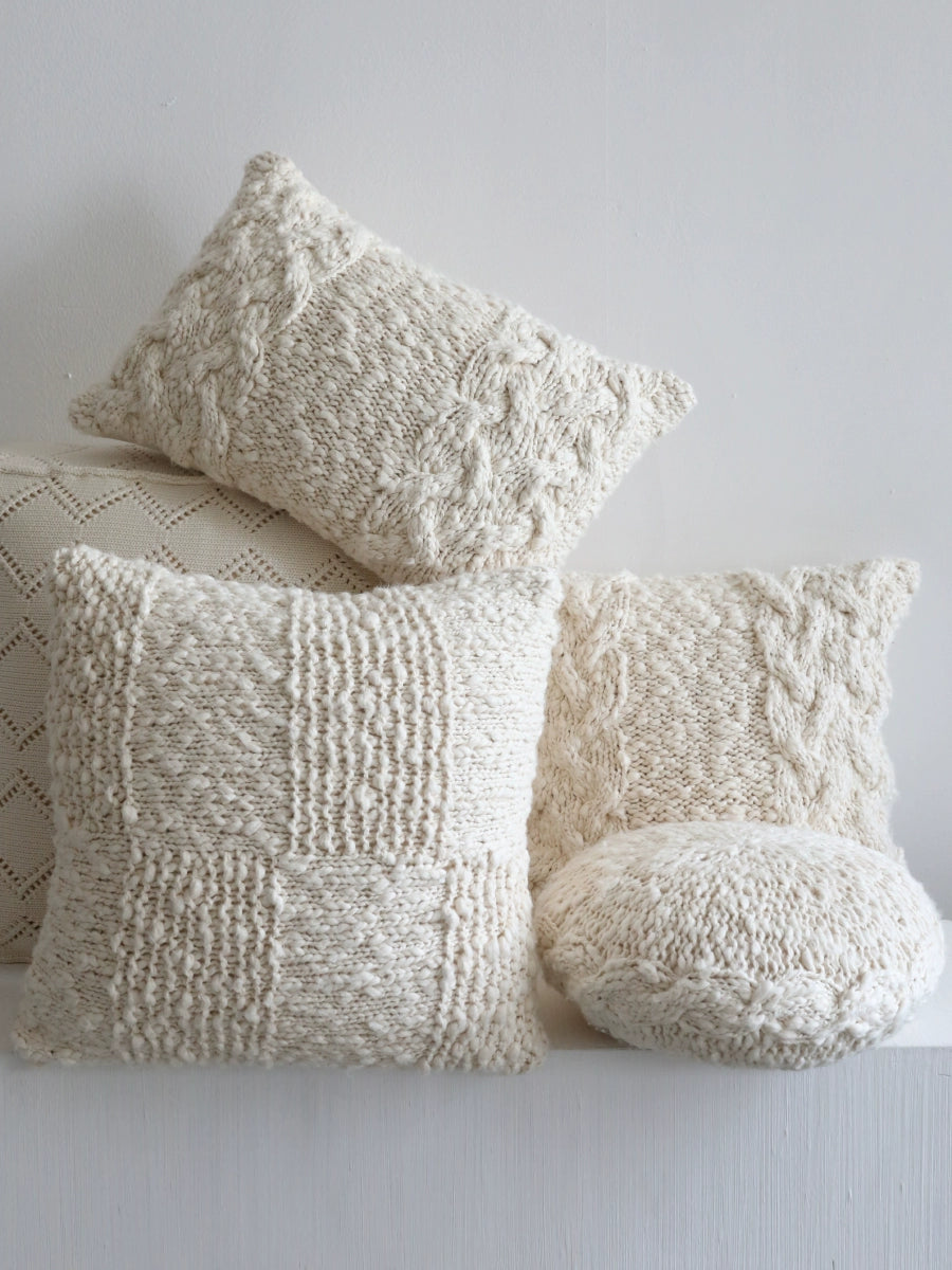 Set of 4 cream knitted throw pillows with various textures and cable knit designs.  Cozy decorative pillows for sofa, chair, or bed.