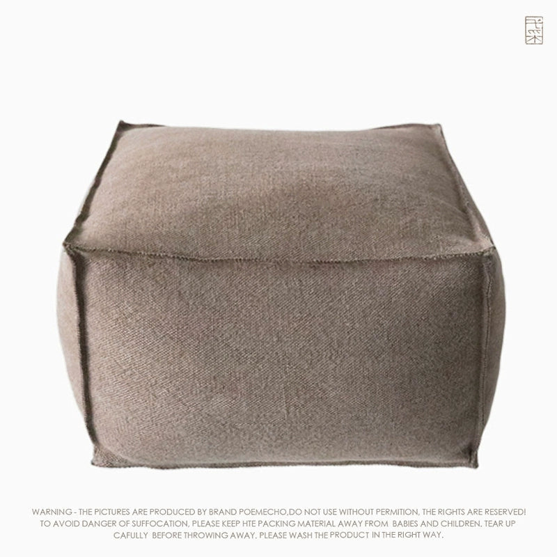 Light taupe square knitted pouf ottoman, showing stitched edges.