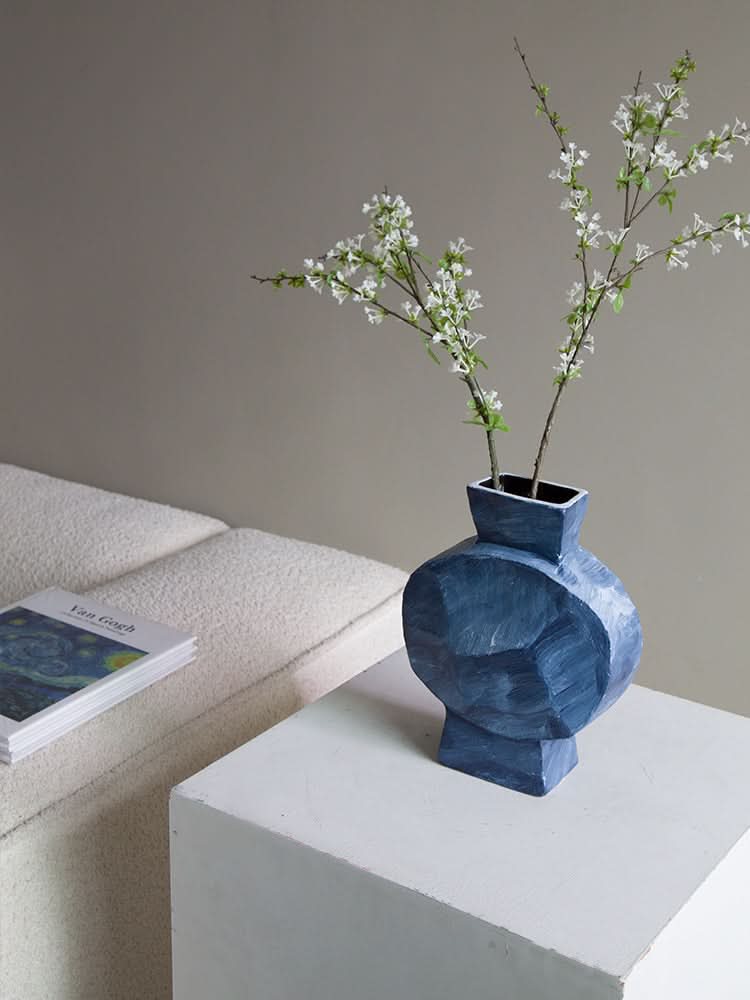 Dreamy Abstract Vase: Blue geometric vase with white blossoms on a white cube.