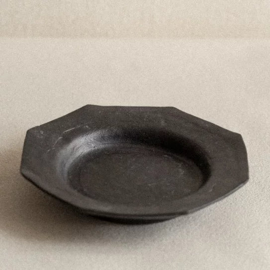 Octagonal matte black ceramic plate with a wide rim and central basin.