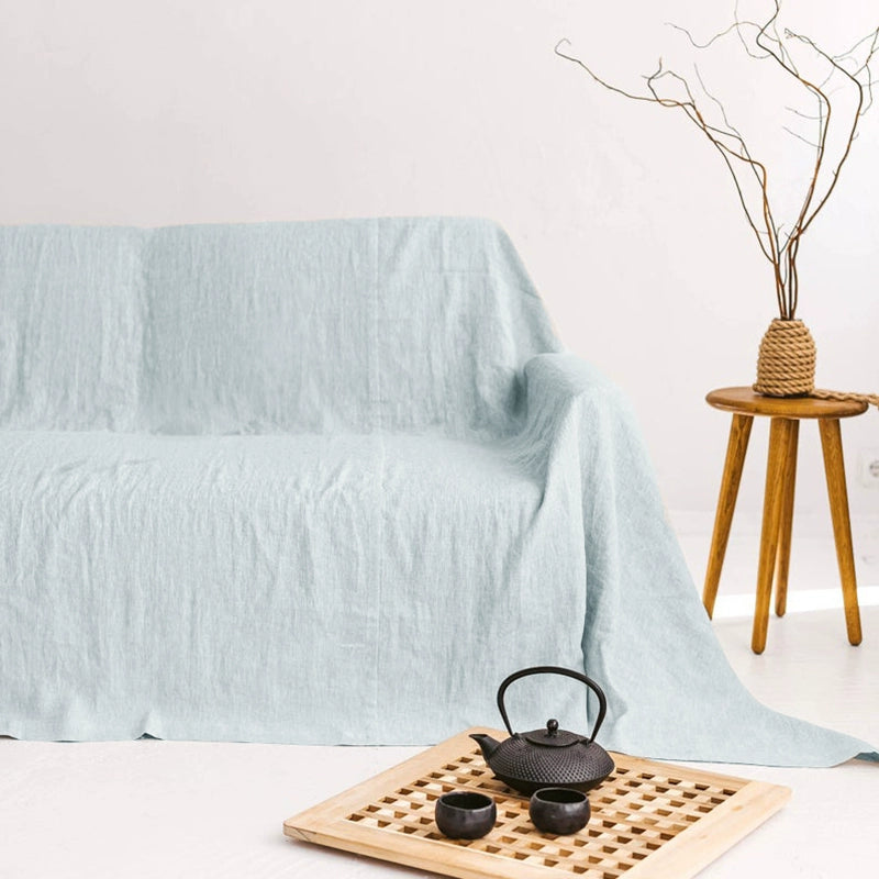 Light blue linen sofa throw blanket draped over couch, cozy living room decor.