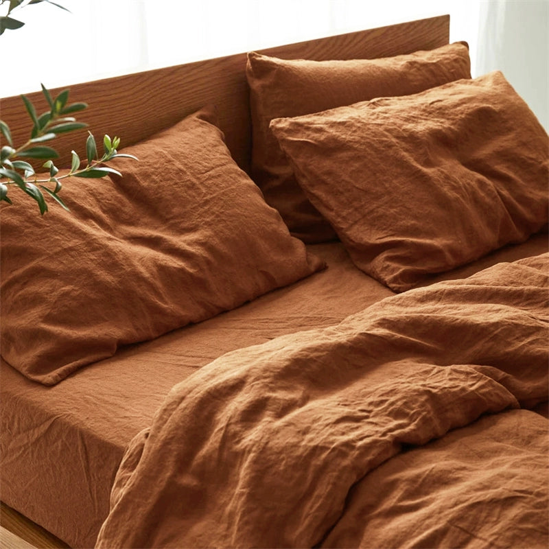 Natural linen bedding set in rust color, soft & comfortable, with pillows and duvet on a wooden headboard.