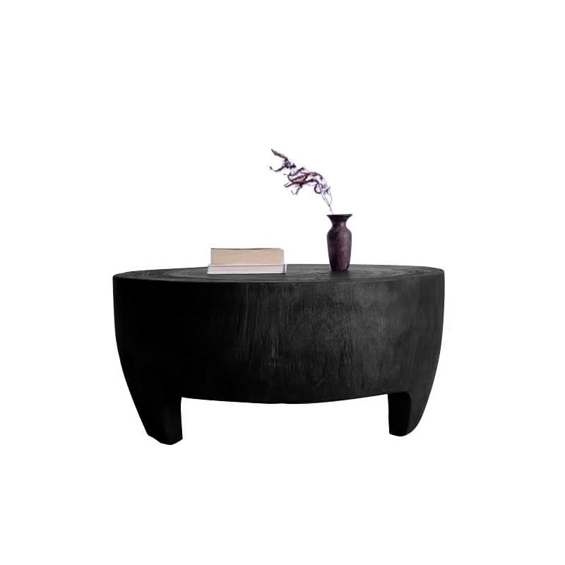 Dark raw wood coffee table, rustic and unique design, with books and a vase.