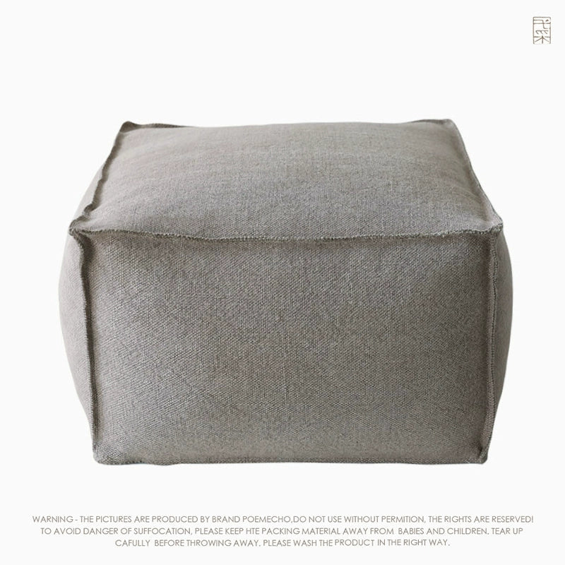 Light gray square knitted pouf ottoman, featuring clean lines and visible stitching.  Modern boho style.