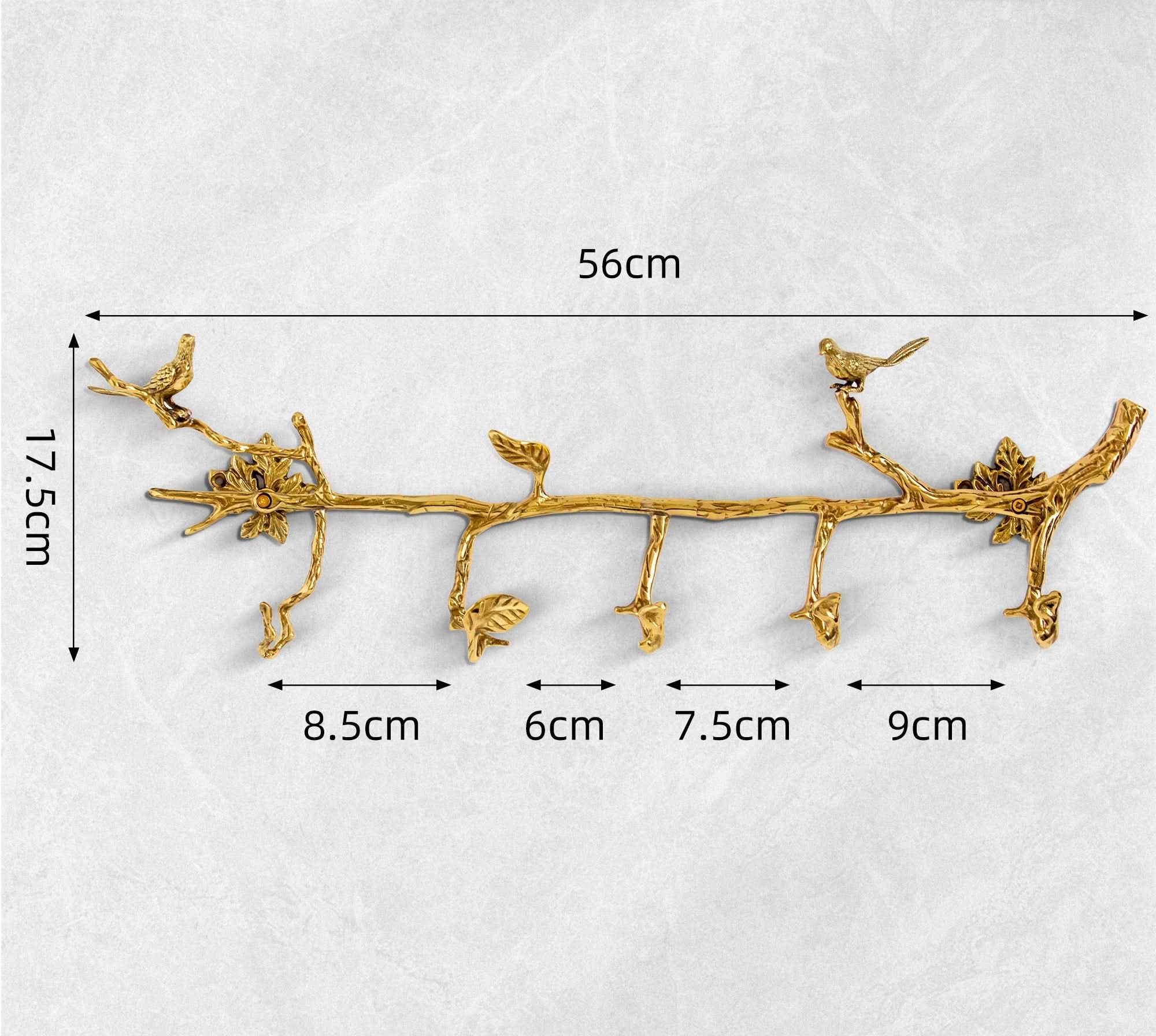 Vintage brass bird branch wall hooks with leaf accents, on a gray textured background.