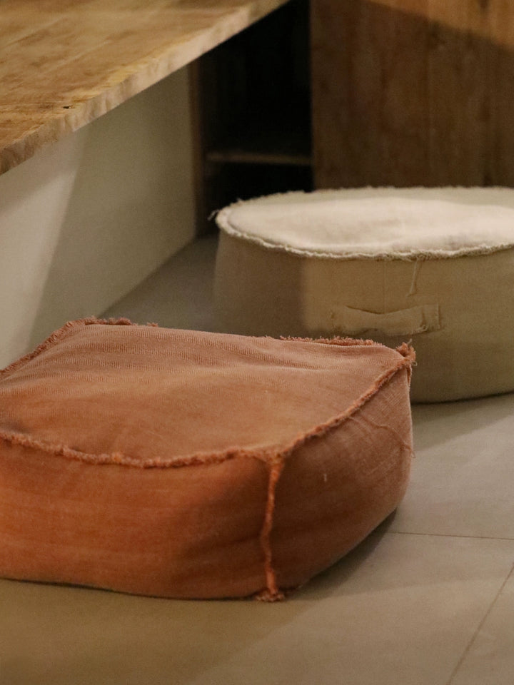 Rustic taupe square fabric ottoman, featuring a unique, slightly distressed edge.  Perfect for living room or meditation space.