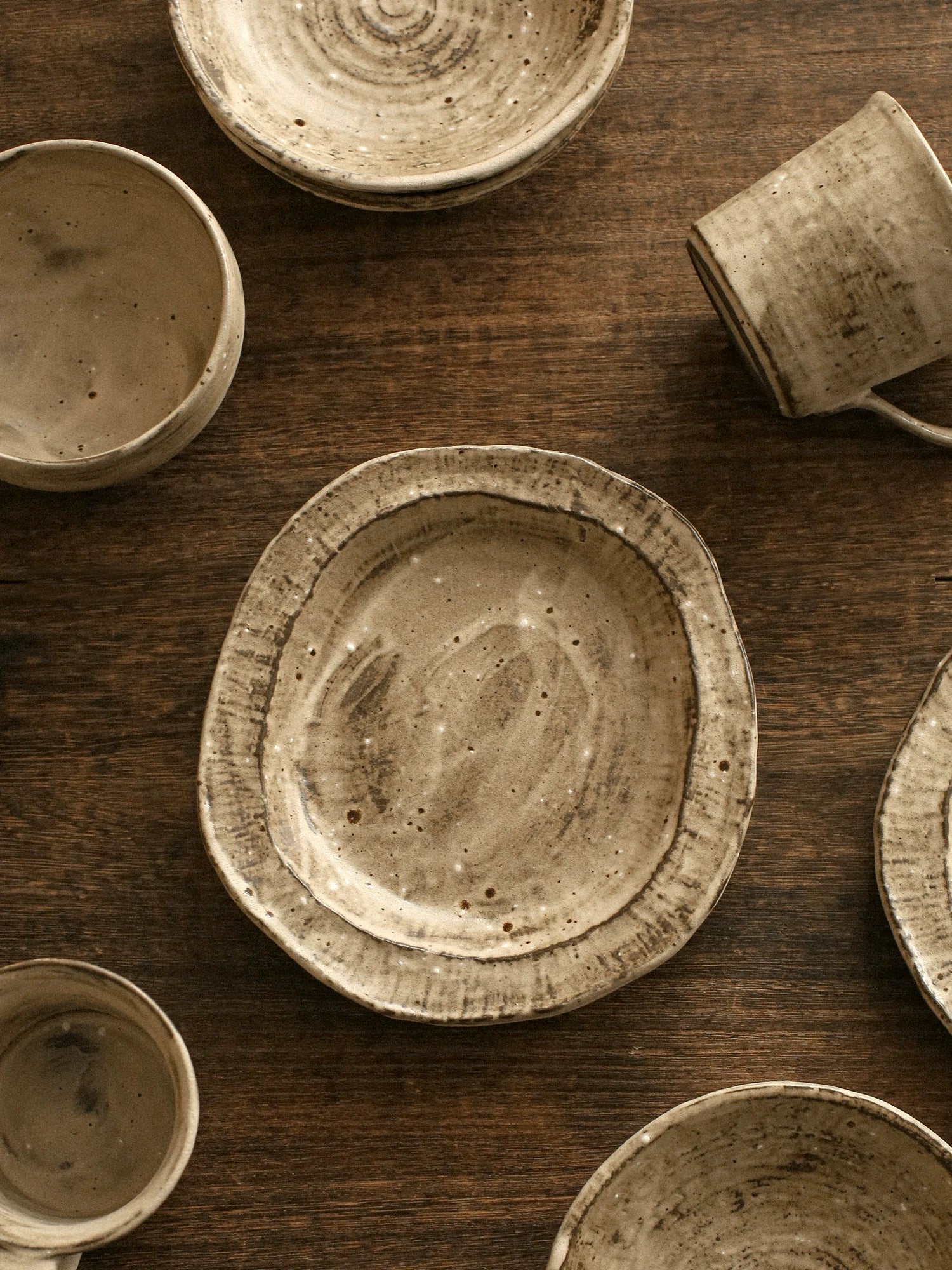 A coarse pottery bowl with a mottled green glaze and irregular rim sits on a dark surface.