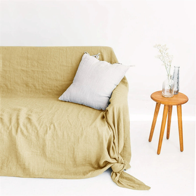 Mustard yellow linen sofa throw blanket with light grey pillow on a couch. Cozy home decor.
