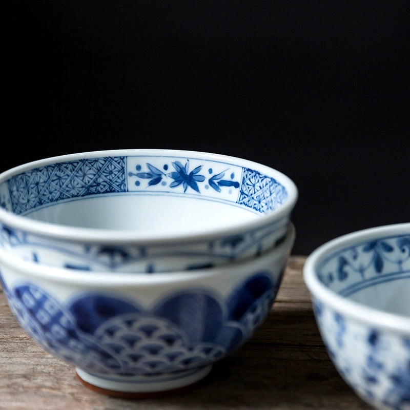 Blue and white floral porcelain bowls set, traditional Chinese design, on wooden surface.