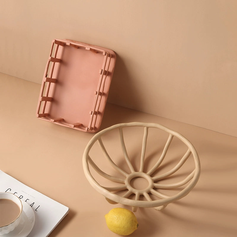 Beige/peach hand-carved ceramic fruit basket with openwork design.  Durable, decorative storage bowl.  Light peach and beige tones.  Studio shot.
