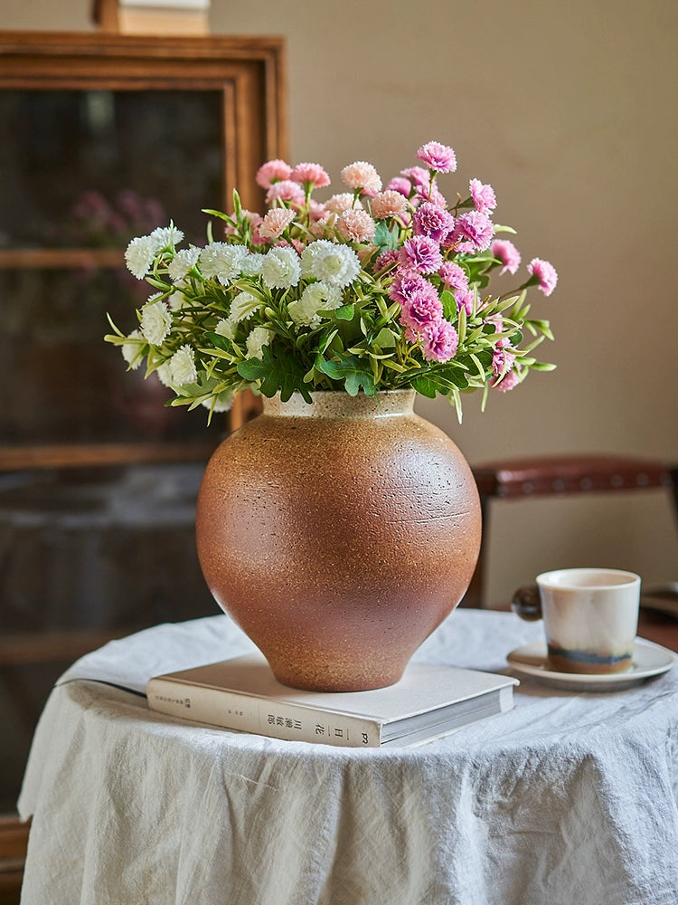 Rustic brown handmade pottery vase, filled with pink and white flowers.  Unique texture and glaze.  23cm high.