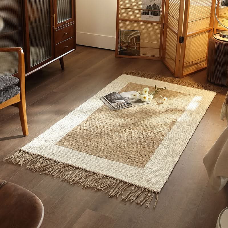 Natural jute rug with navy stripes and fringe detail, styled with books and flowers on a wooden floor.