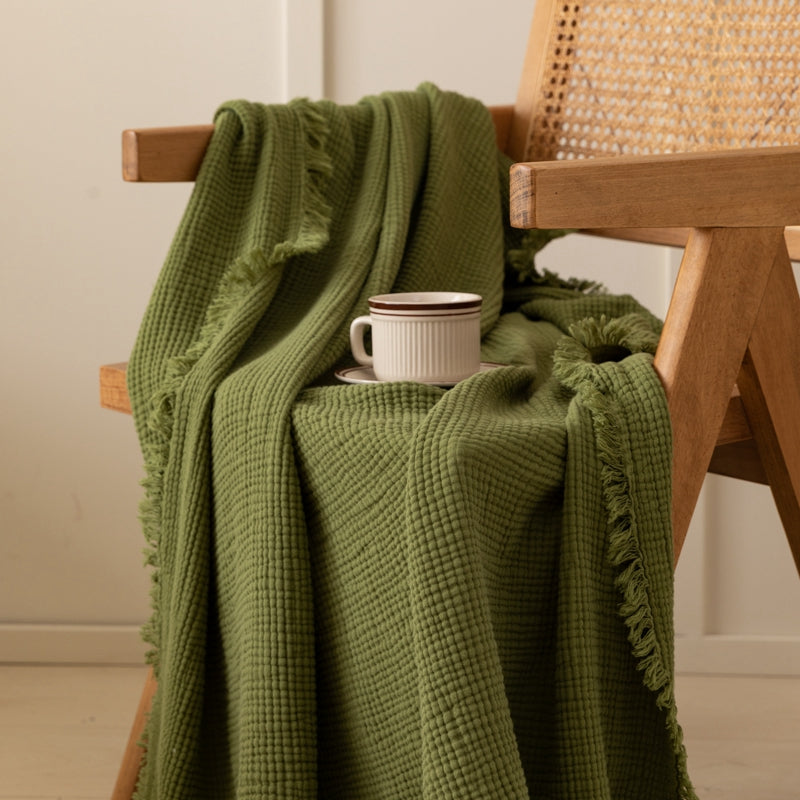 Mustard yellow throw blanket draped over a wooden chair.  A white coffee cup sits on a saucer.