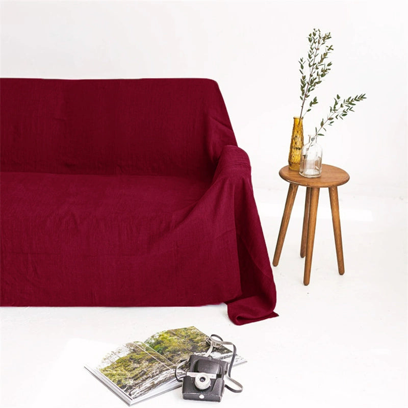 Maroon linen sofa throw blanket draped over a sofa with a small wooden table and decor.