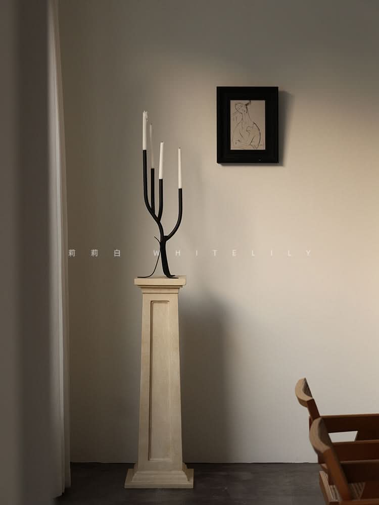 Black modern branch candle holder with white candles on a wooden pedestal, home decor.
