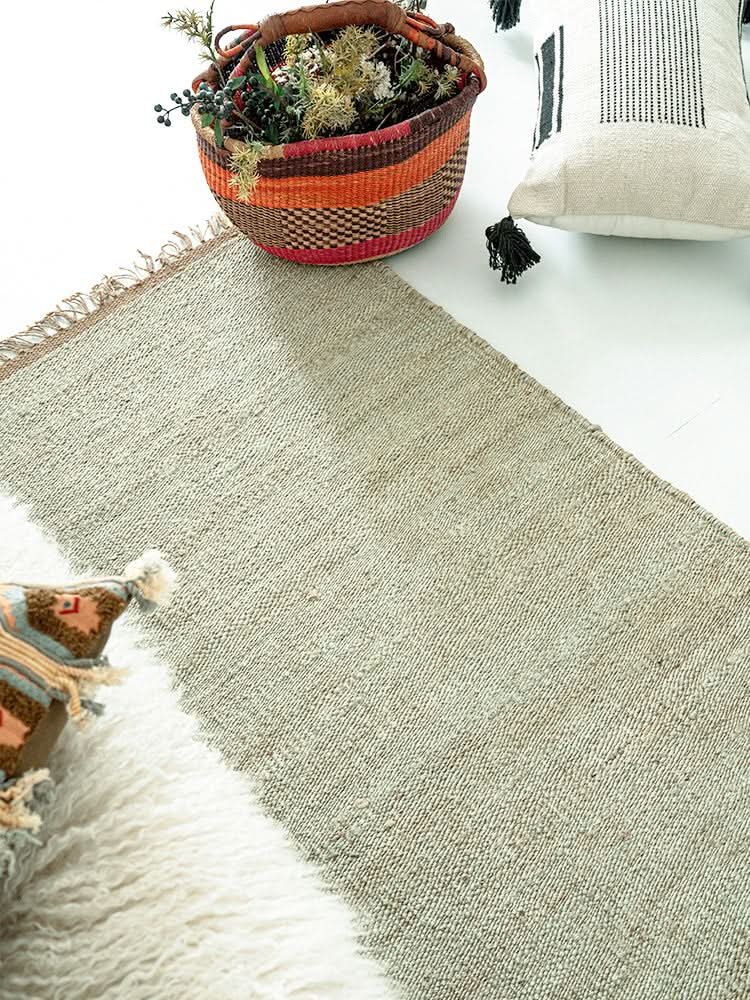 Handwoven Jute Rug - Natural & Rustic texture, earthy tones, with decorative basket and pillows