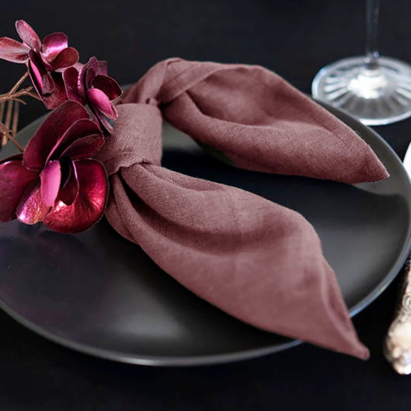 Elegant linen table napkins, knotted rose color, with floral accent on black plate. Set of 4.