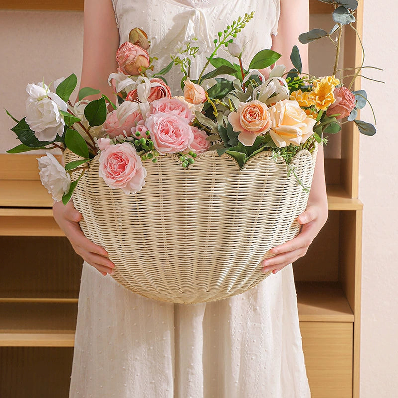 Beige scalloped wicker wall basket overflowing with pastel flowers. Decorative home decor.