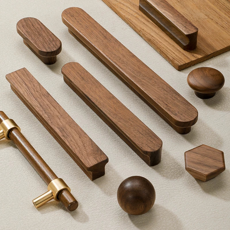 Assortment of walnut wood cabinet pulls and knobs with brass accents on a light surface.