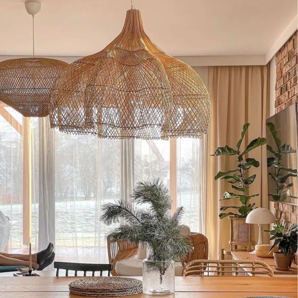 Natural rattan pendant light with teardrop shape hangs in a room with natural light and plants.