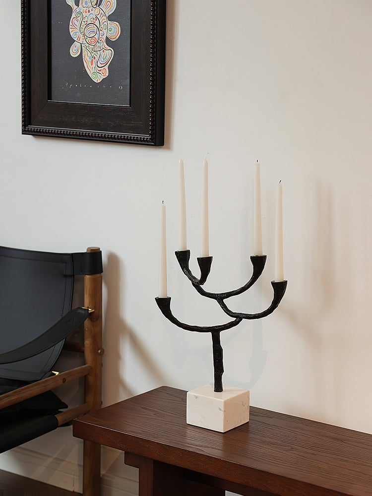Modern black metal & marble candle holder with five white taper candles on a wooden table.