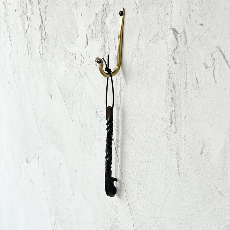 Gold J-Shaped Wall Hook with twisted decorative element hanging from it.