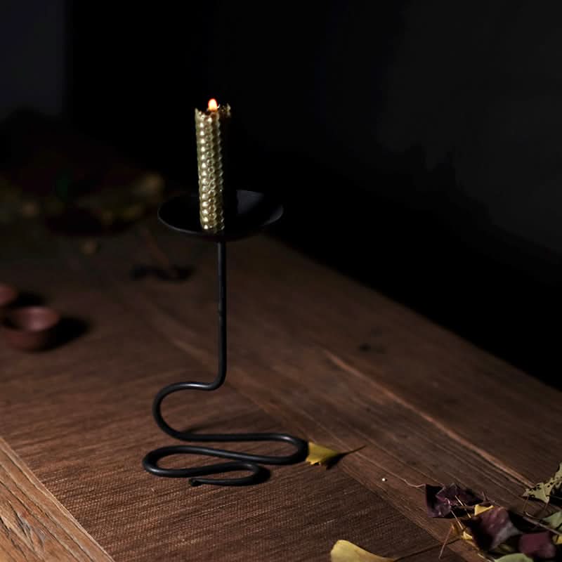 Black Metal Curved Candle Holder with golden candle on wooden table.