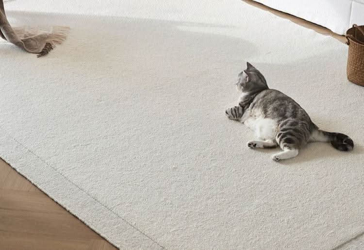 Natural handwoven New Zealand wool rug in cream, with a grey tabby cat relaxing on it.