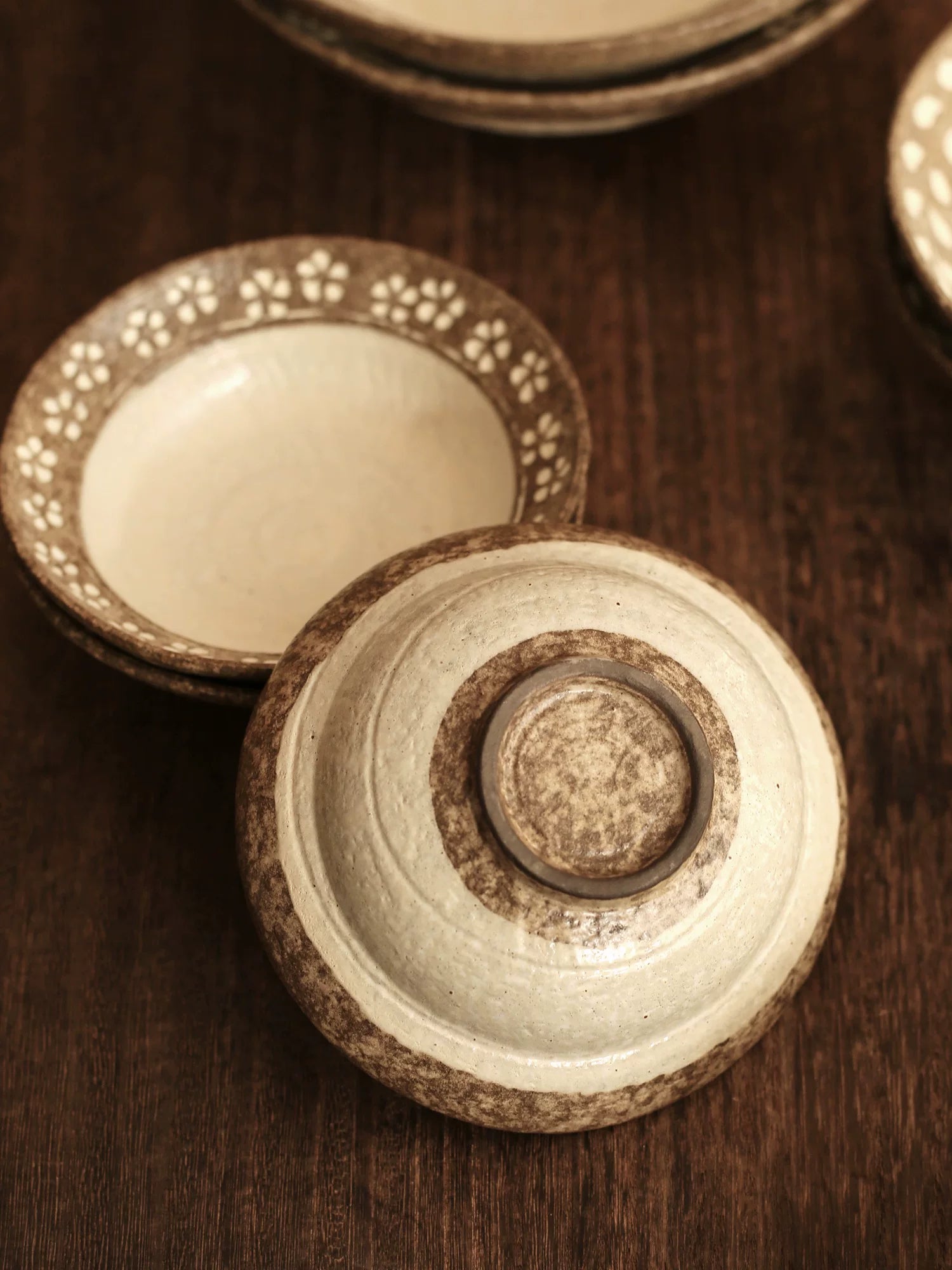 Overhead view of the base of a rustic ceramic bowl with brown floral rim and cream center.