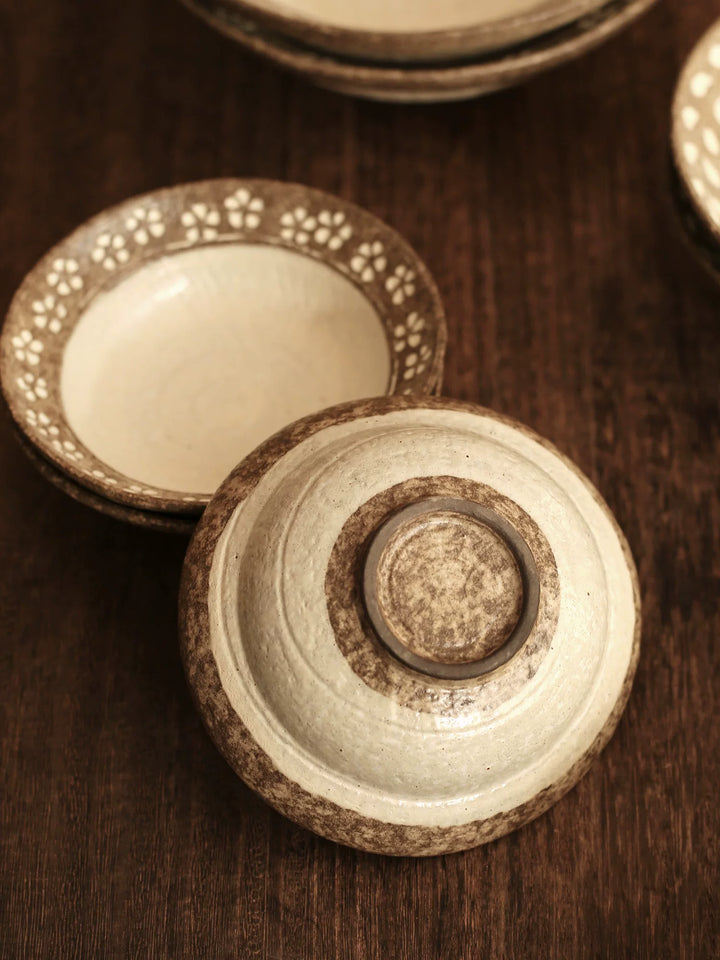 Overhead view of the base of a rustic ceramic bowl with brown floral rim and cream center.