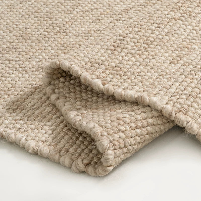 Folded warm beige wool rug highlighting cozy woven texture