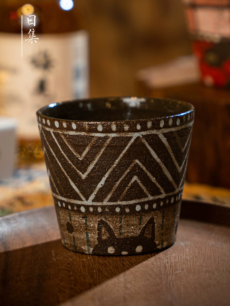 Traditional Japanese hand-painted ceramic tea cup with cat design on wooden tray.
