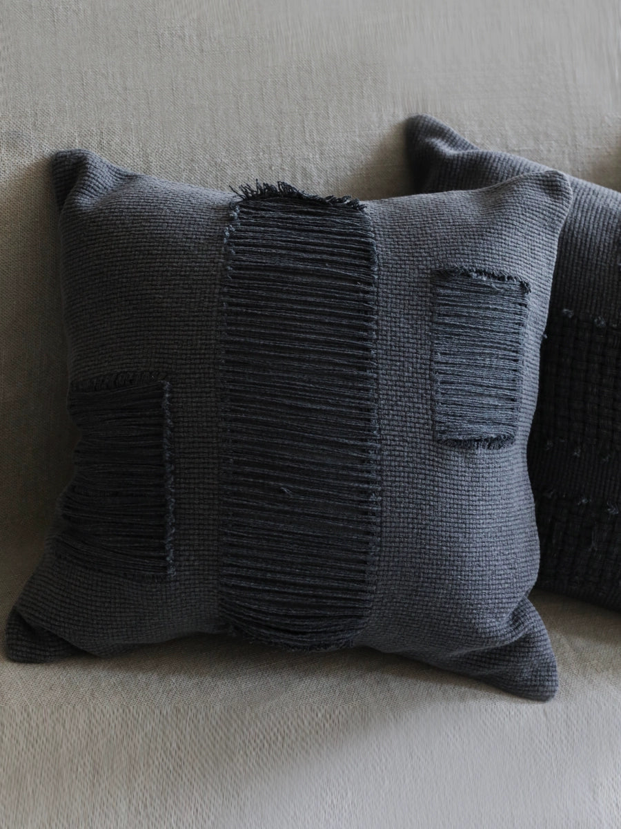 Stylish woven throw pillow in dark gray with textured stitching, perfect for modern boho decor.