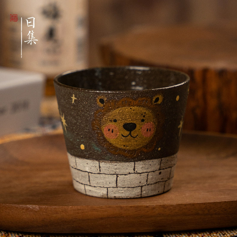 Traditional Japanese hand-painted ceramic cup with lion design, dark glaze, on wooden tray.