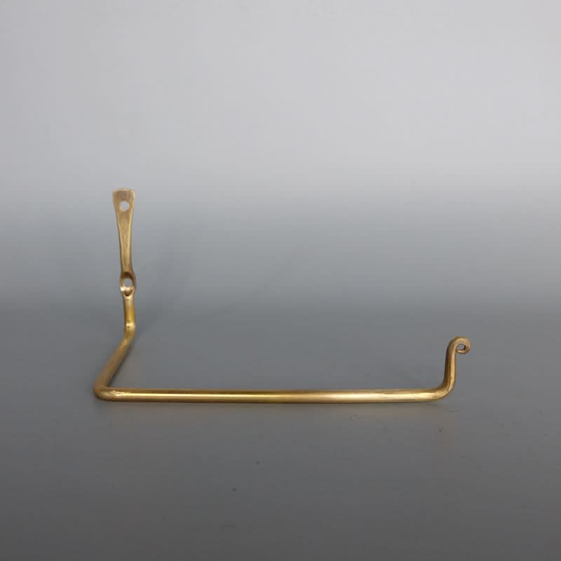 Polished gold toilet paper holder, L-shaped wall mount with decorative curl end.