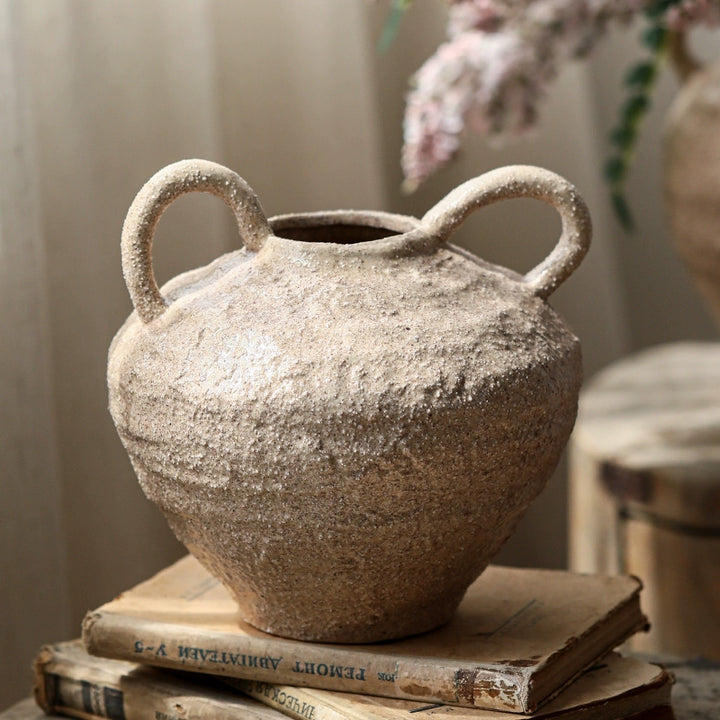 Rustic beige ceramic vase with textured surface and two handles. Handcrafted pottery home decor.